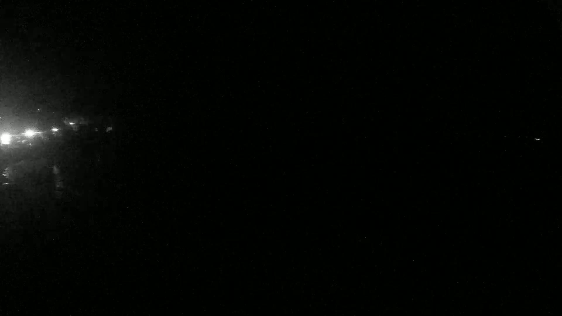Faint lights are visible in the distance on a very dark night.