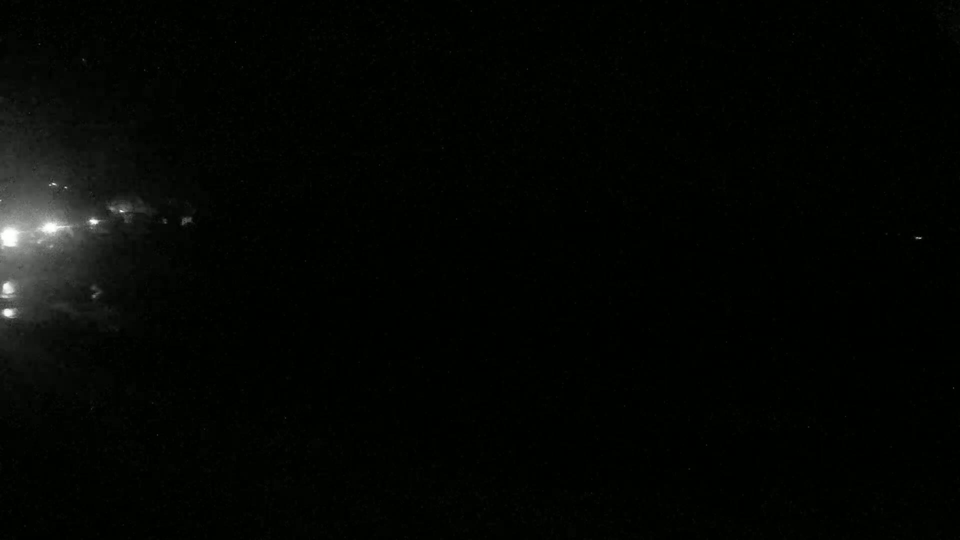 Bright lights appear on the left side of a dark, nighttime scene.