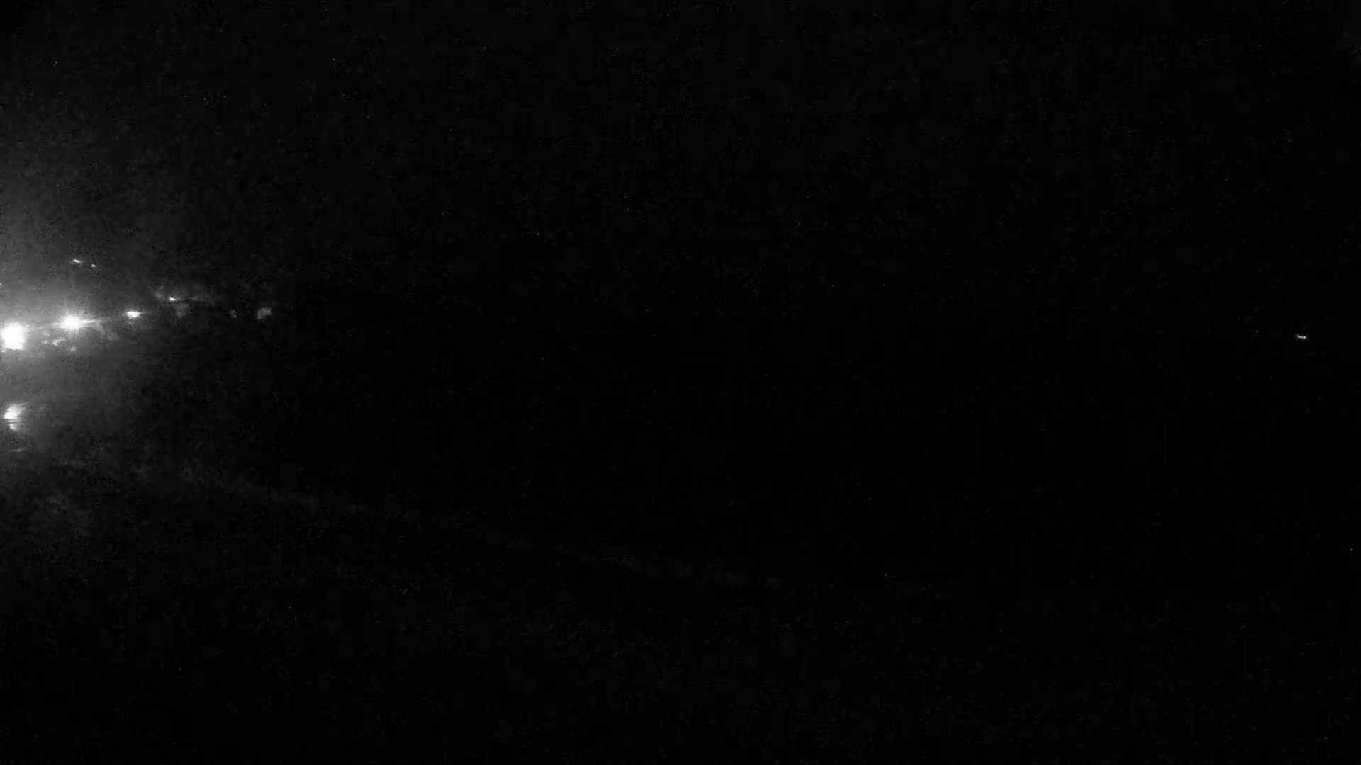 A nighttime, blurry view of bright lights in the distance on the left.
