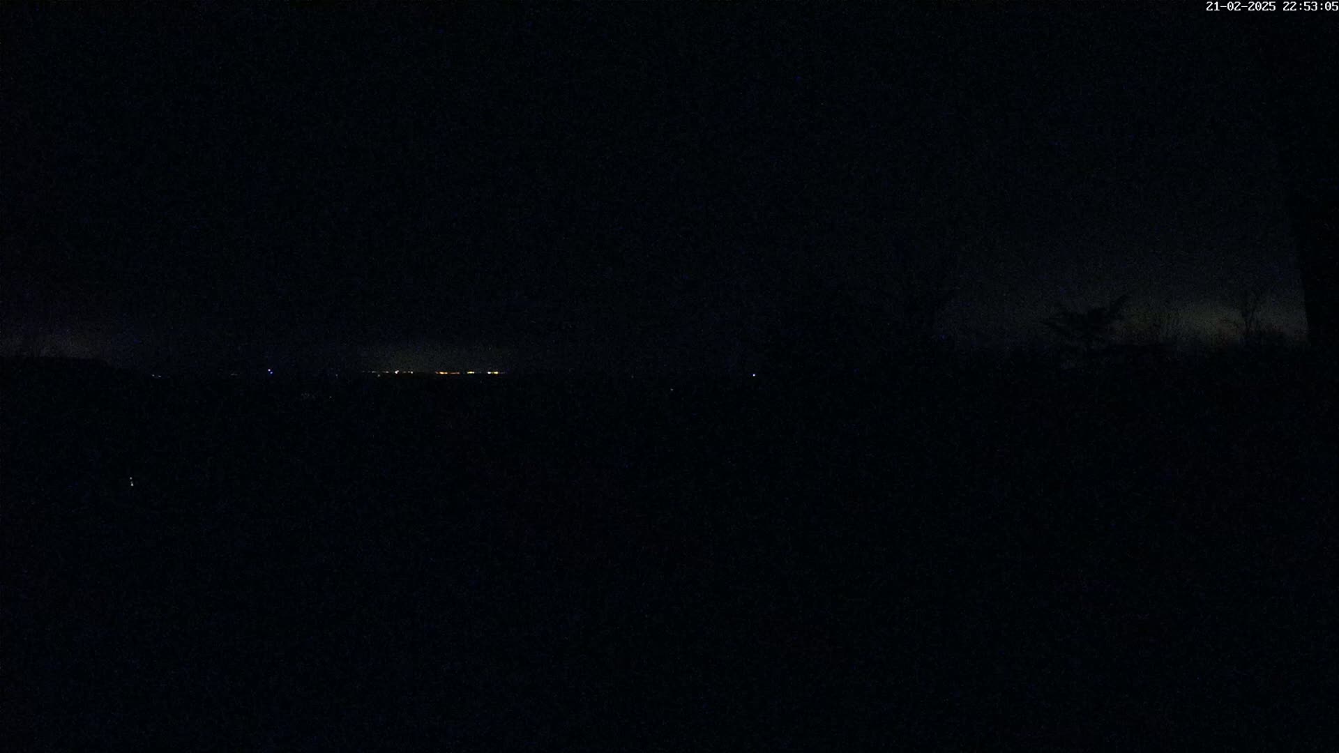 A dark, nighttime scene shows a distant, faintly lit horizon.