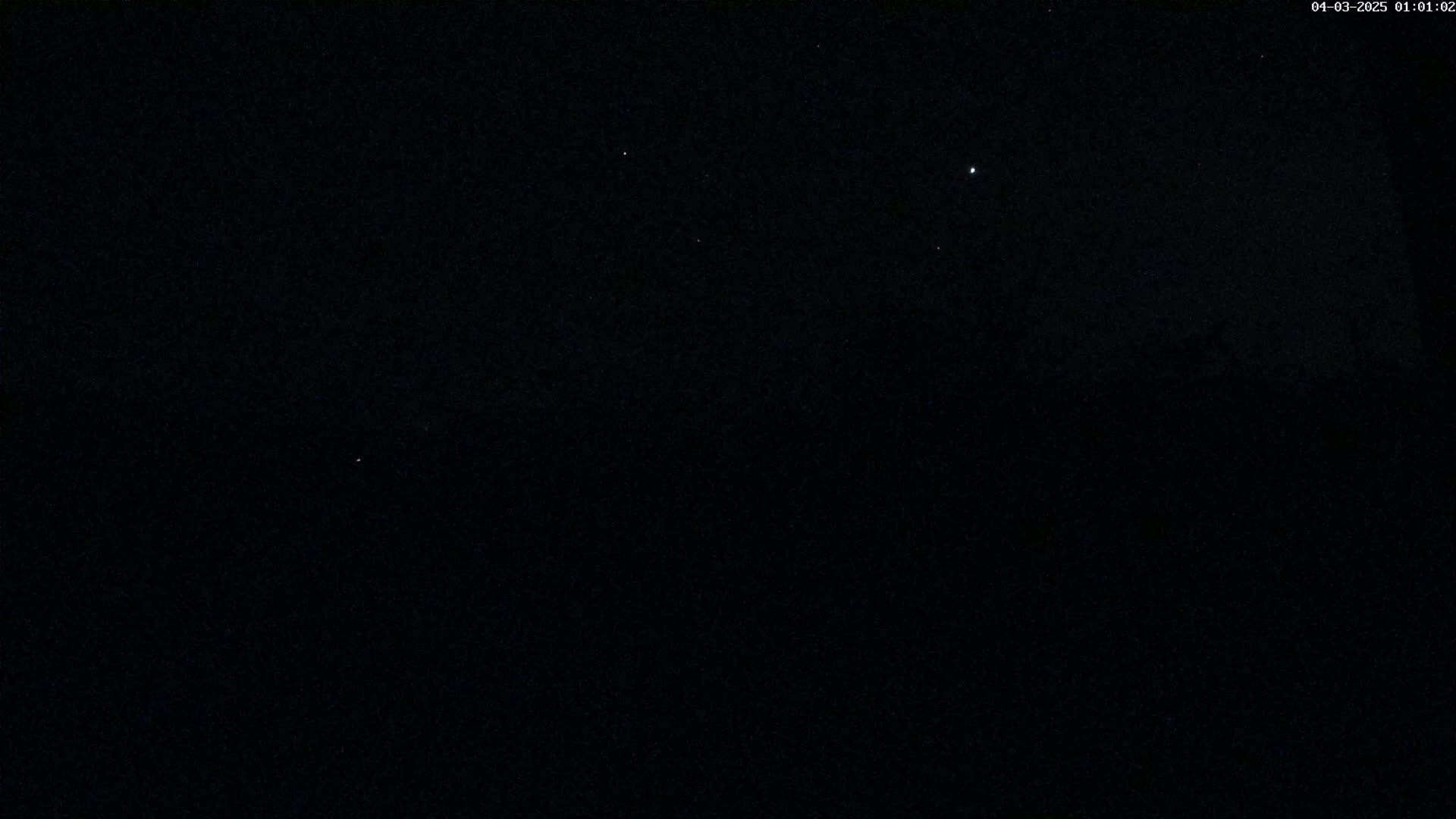 A dark nighttime scene shows a few faint stars in a clear sky.