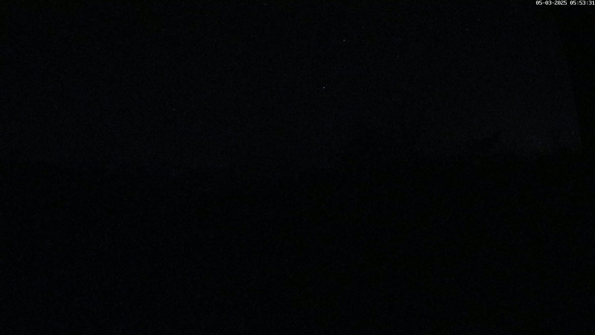 A mostly dark image shows a night sky with a few faint stars.