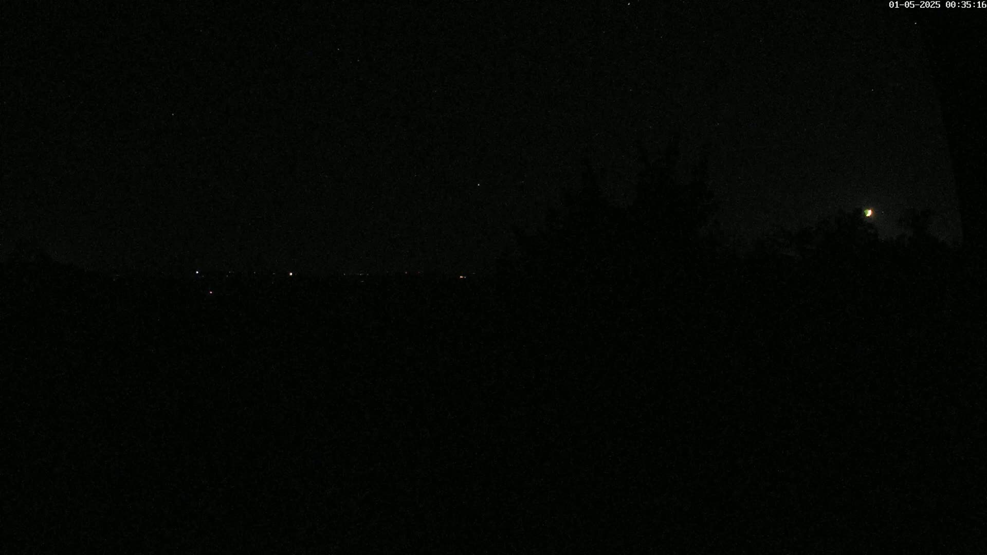 A nighttime view shows a crescent moon in the upper right corner above a dark, silhouetted landscape with a few distant lights.