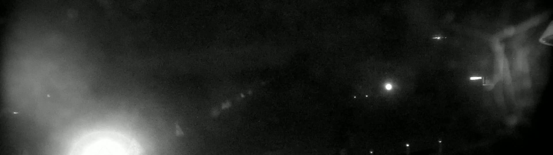A nighttime, blurry image shows several bright lights in the distance and a hazy or foggy atmosphere.