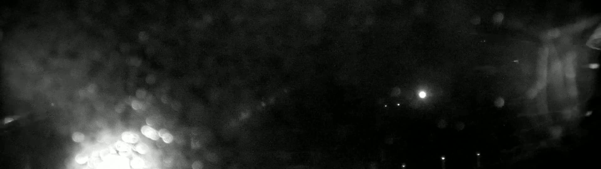 Blurry lights are visible through a rain-streaked window at night.