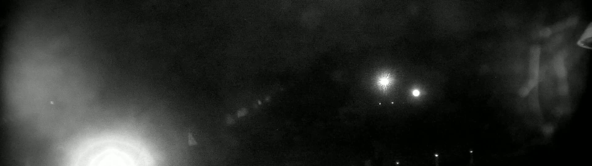 A blurry, nighttime image shows several bright lights in the distance, possibly from streetlights or vehicles.