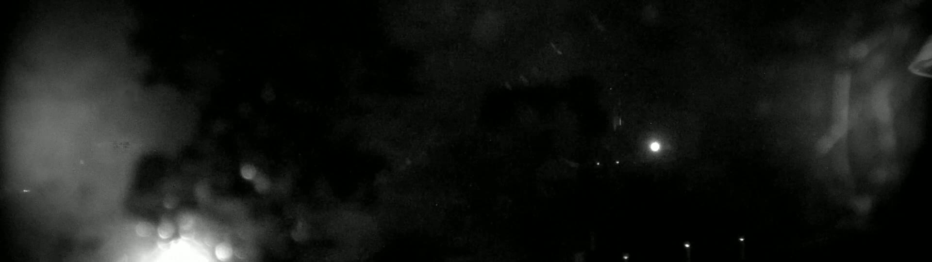 A blurry, dark, nighttime image shows indistinct shapes and bright lights in the distance.