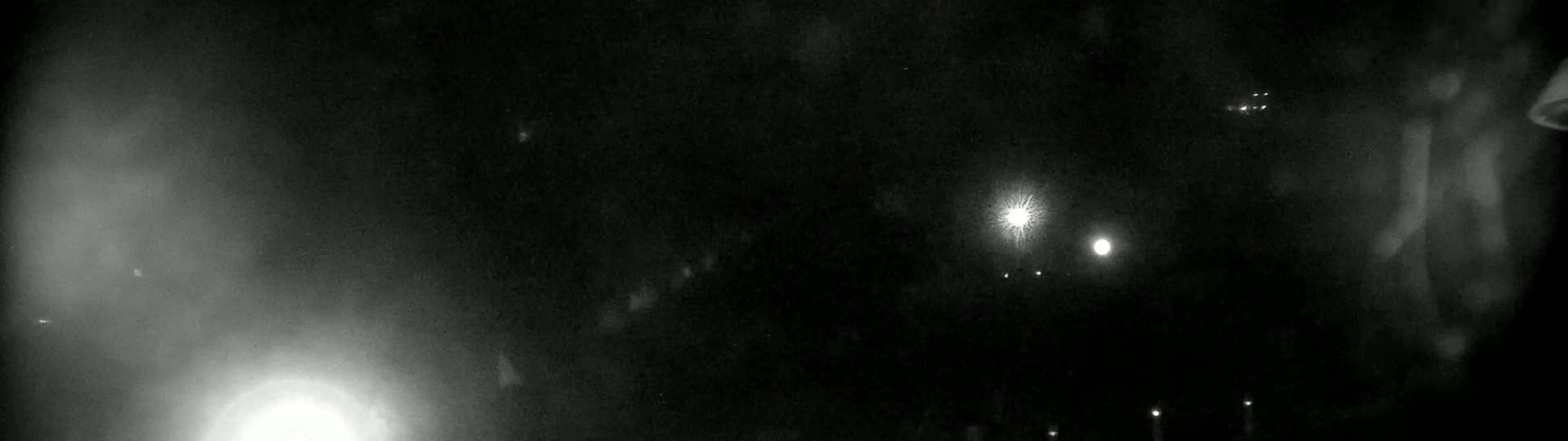 A nighttime, blurry image shows several bright lights and a hazy, dark sky.
