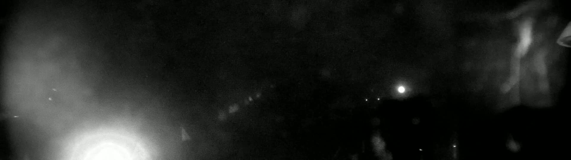 A blurry, dark, nighttime image shows several indistinct lights in the distance and a brighter light closer to the bottom left.