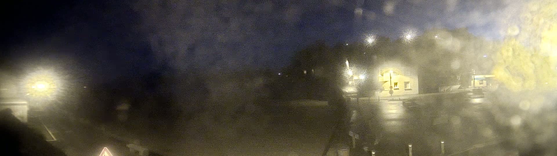 A blurry nighttime scene of buildings and lights viewed through a rain-streaked window.