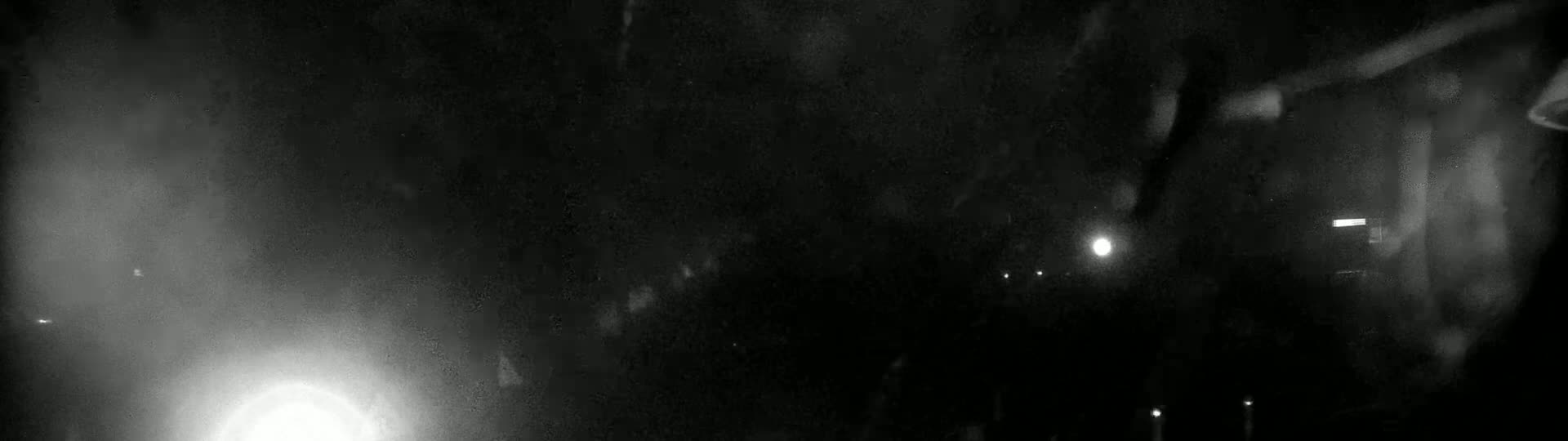 A blurry, dark nighttime scene shows a few indistinct lights through what appears to be rain or condensation on a window.