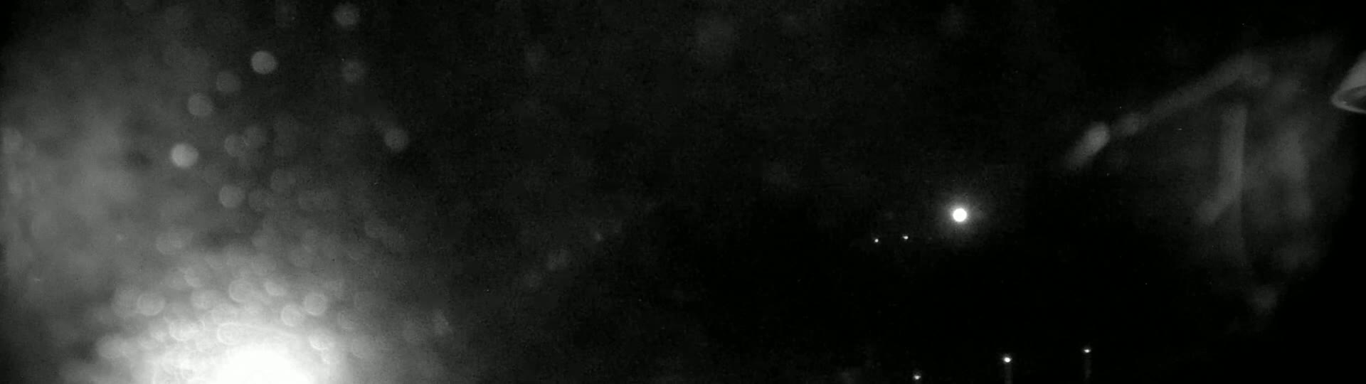 A nighttime, blurry view of out-of-focus lights and what appears to be rain or snow falling.