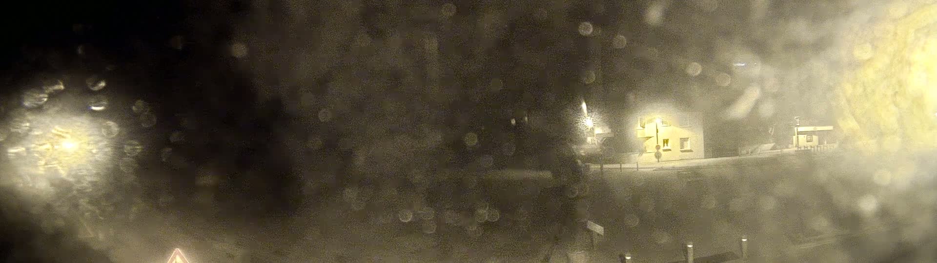 A blurry nighttime view of a building illuminated by a streetlight, obscured by heavy rain or snow.