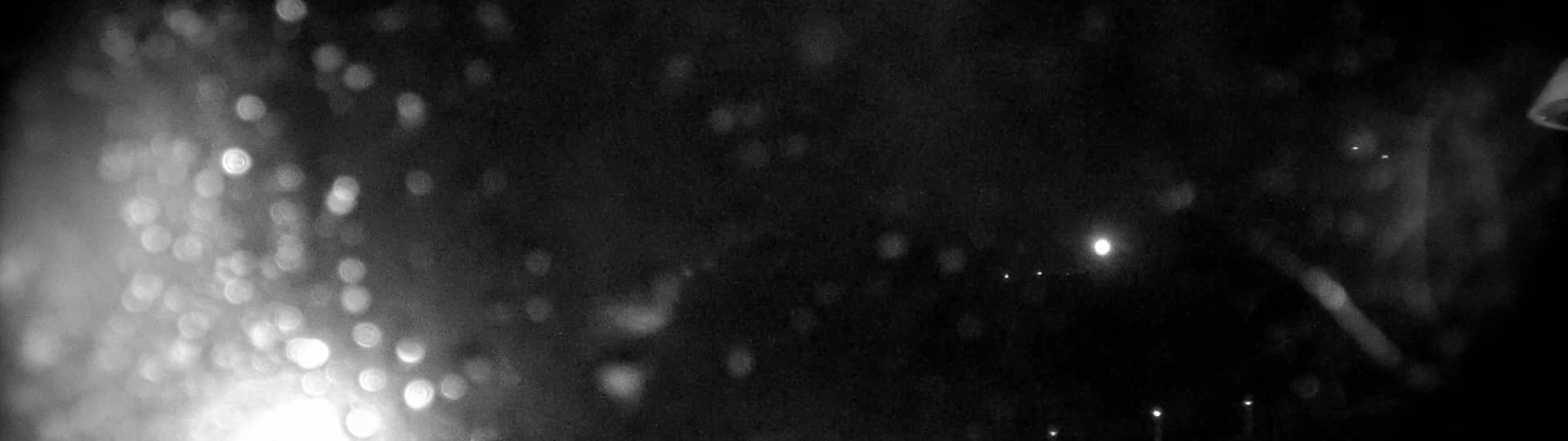 A blurry, nighttime image shows bright out-of-focus lights in the foreground against a dark background.