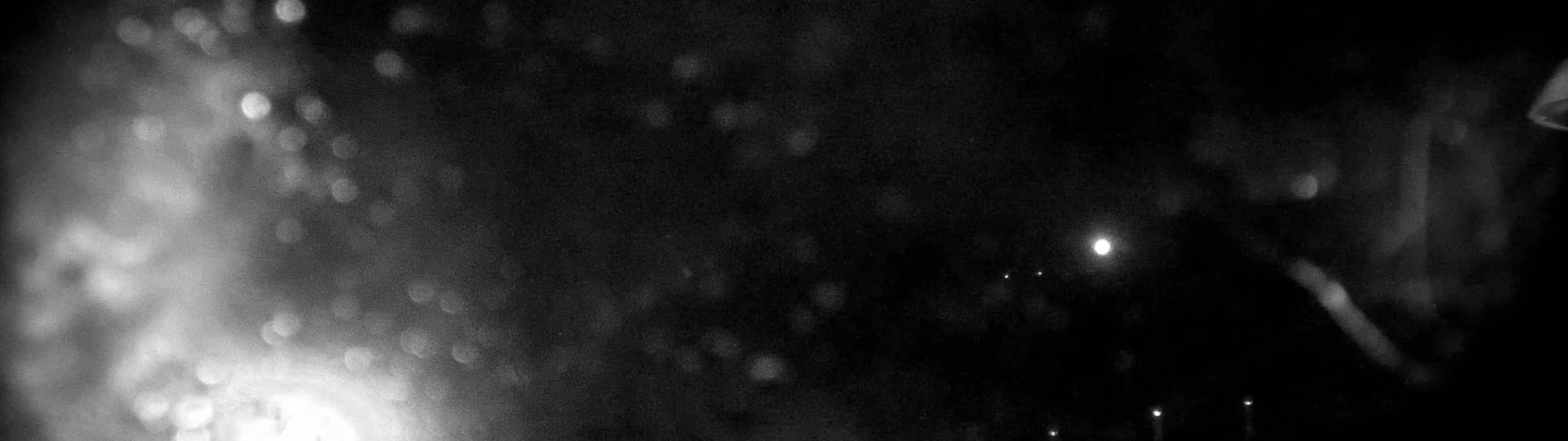 A blurry, out-of-focus nighttime image shows bright lights and indistinct shapes in the dark.
