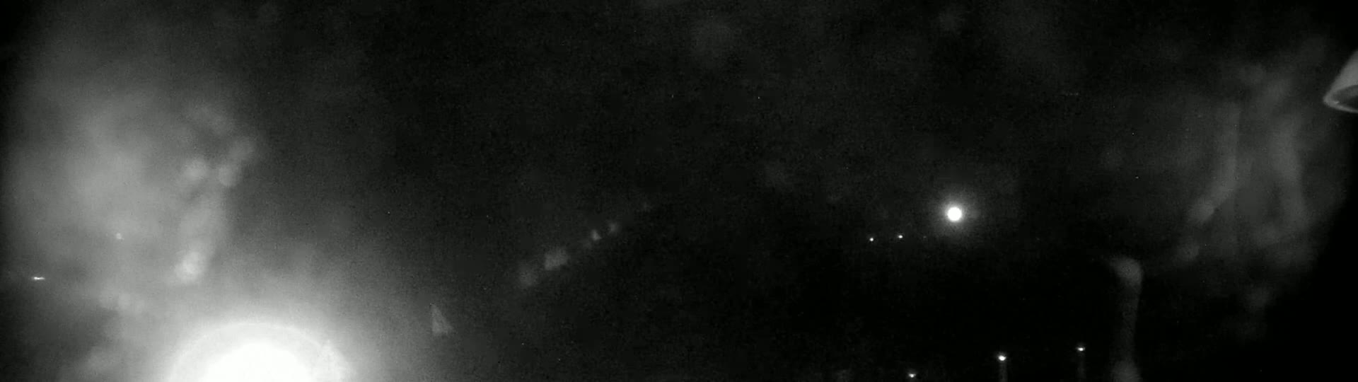 A nighttime view shows hazy or foggy conditions with several bright lights visible in the distance.