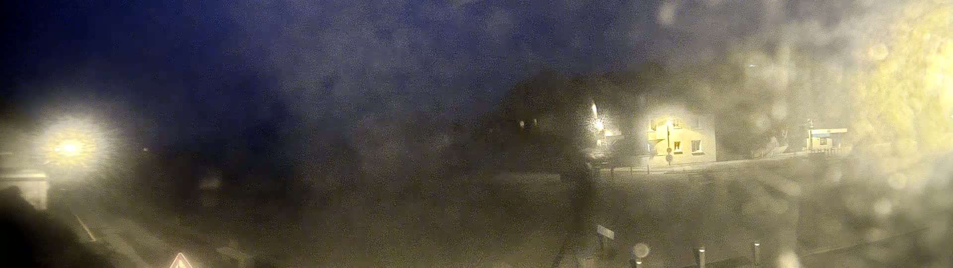 A blurry nighttime view of a building and road, obscured by rain or fog.