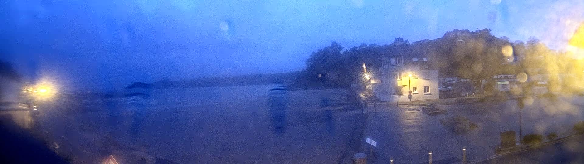 A building is seen across a flooded street at night, viewed through a rain-streaked window.