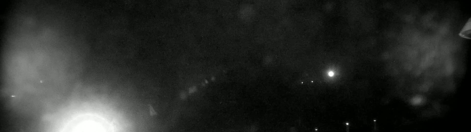 A nighttime, hazy scene shows a few faint lights in the distance.