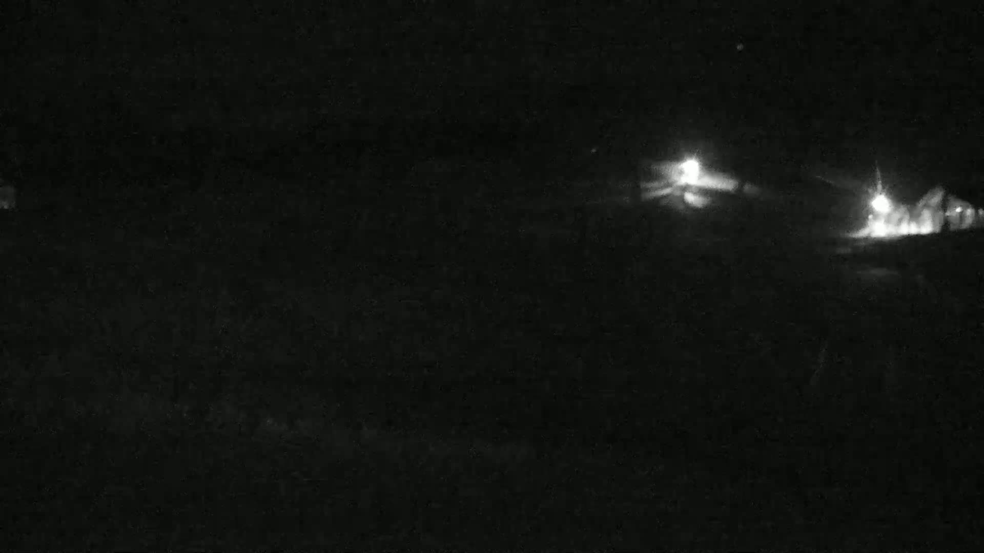 At night, two faintly lit areas are visible in the distance, appearing to be buildings or structures, against a completely dark background.