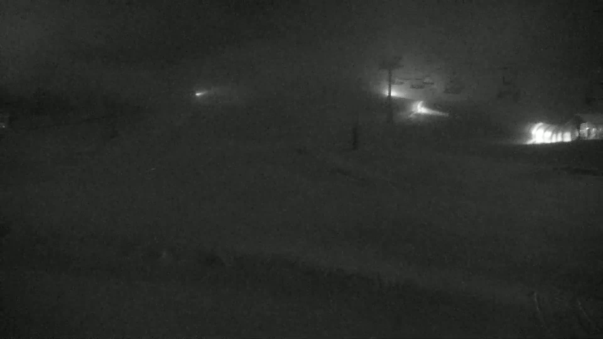 Faintly lit vehicles are visible through heavy nighttime snow.