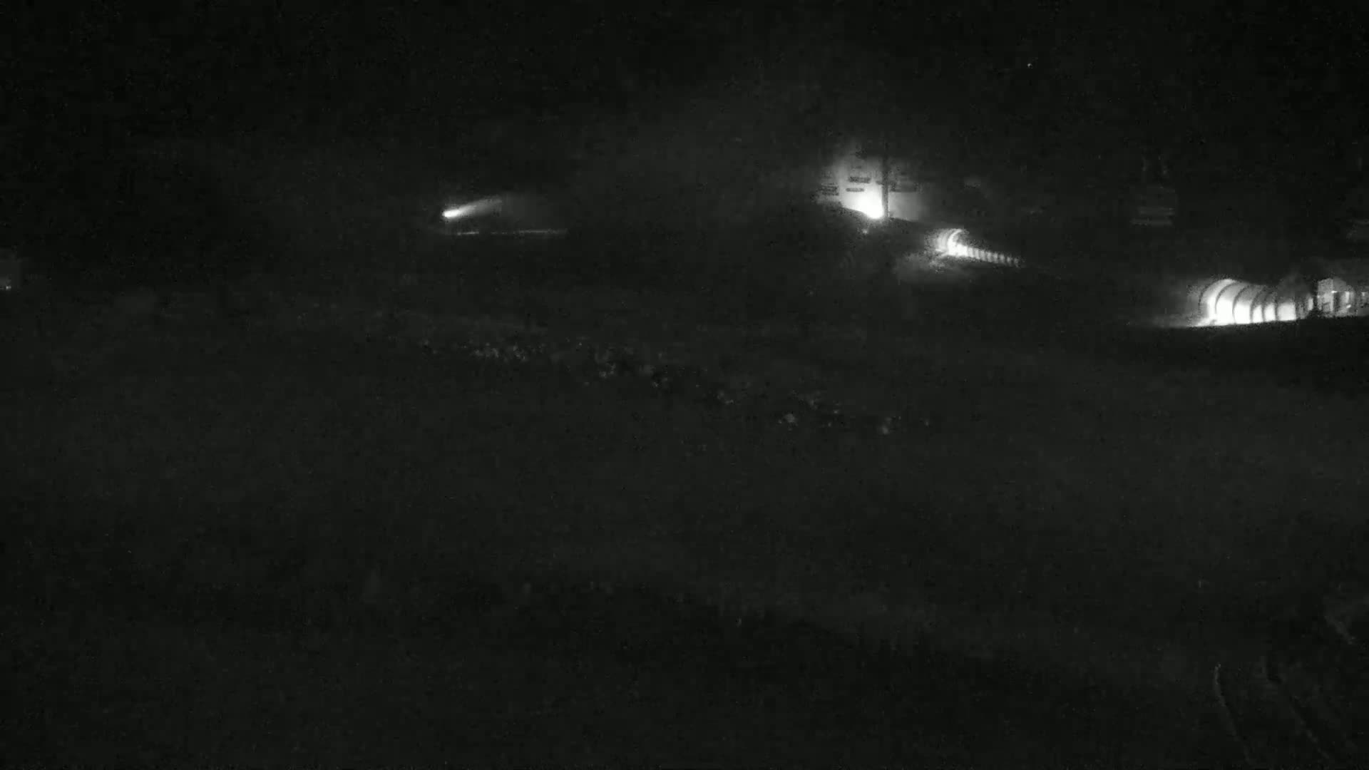 A nighttime, foggy scene shows faintly lit roadways and structures.