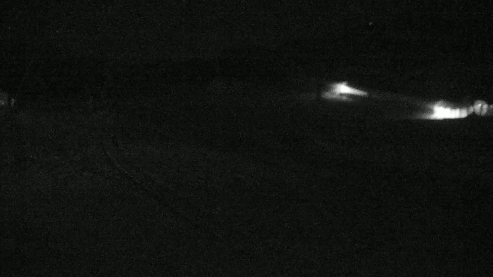 At night, two streaks of light are visible in the distance across a dark, grainy background.