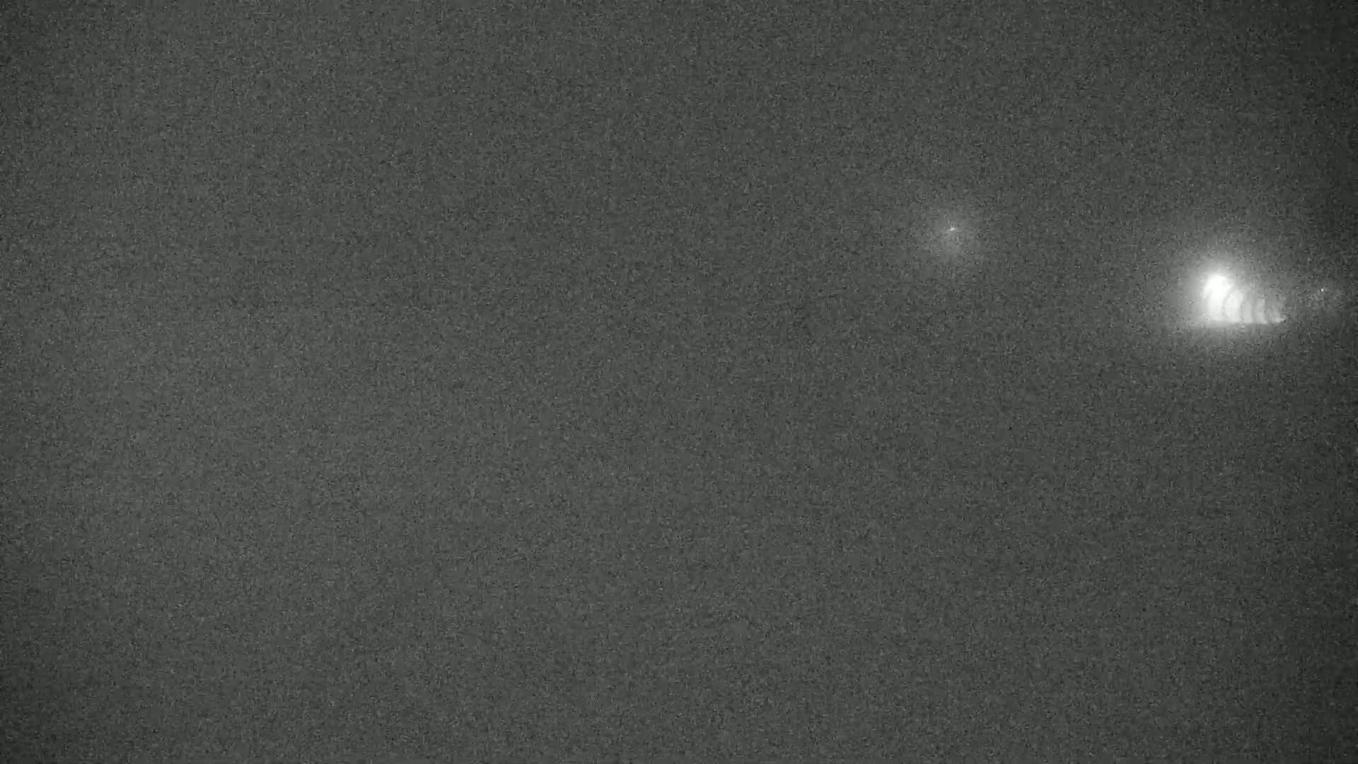 A grainy, dark image shows two bright lights in the distance at night.