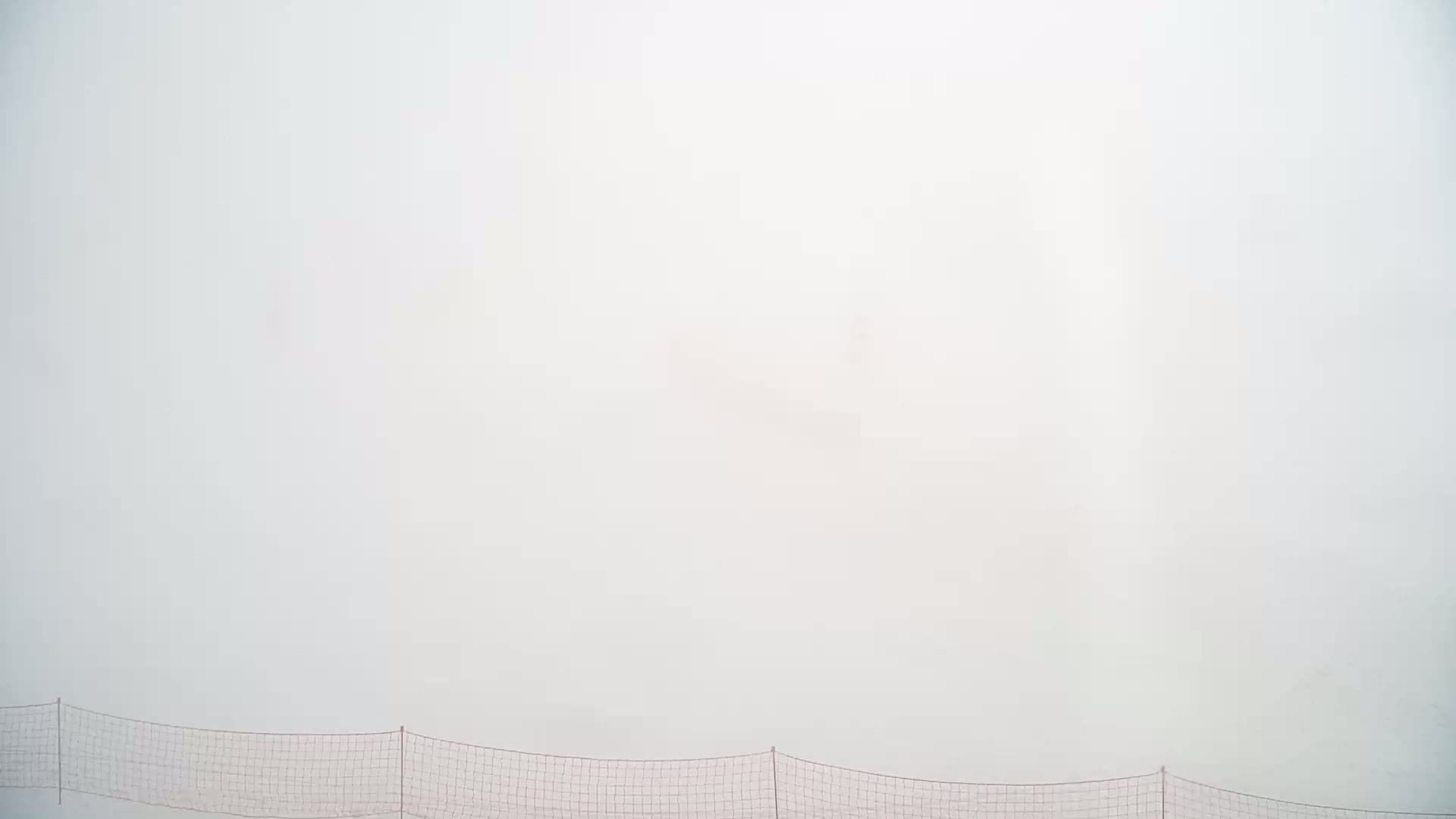 A low-hanging fog obscures the view above a low, horizontal net.