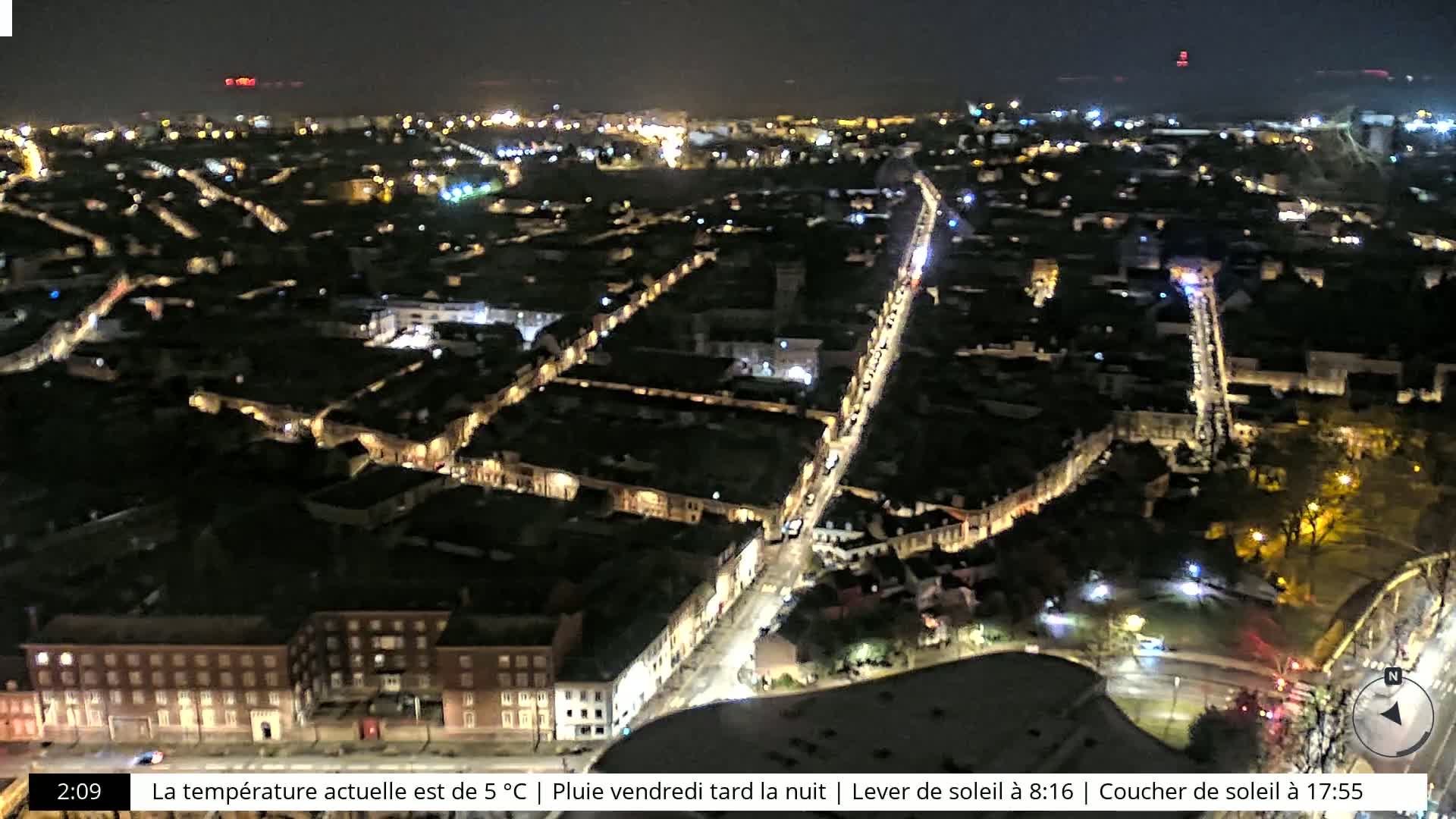 A nighttime aerial view of a city with illuminated streets and buildings under a clear sky.