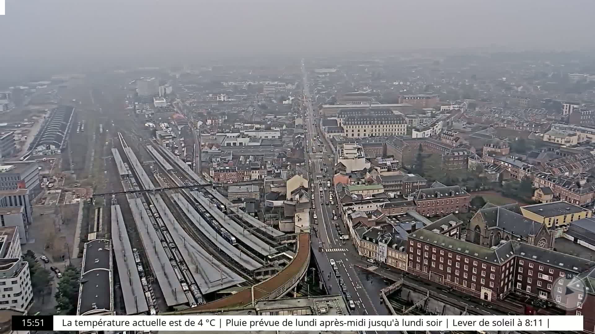 A high-angle, long shot of a city with a train station on an overcast day.