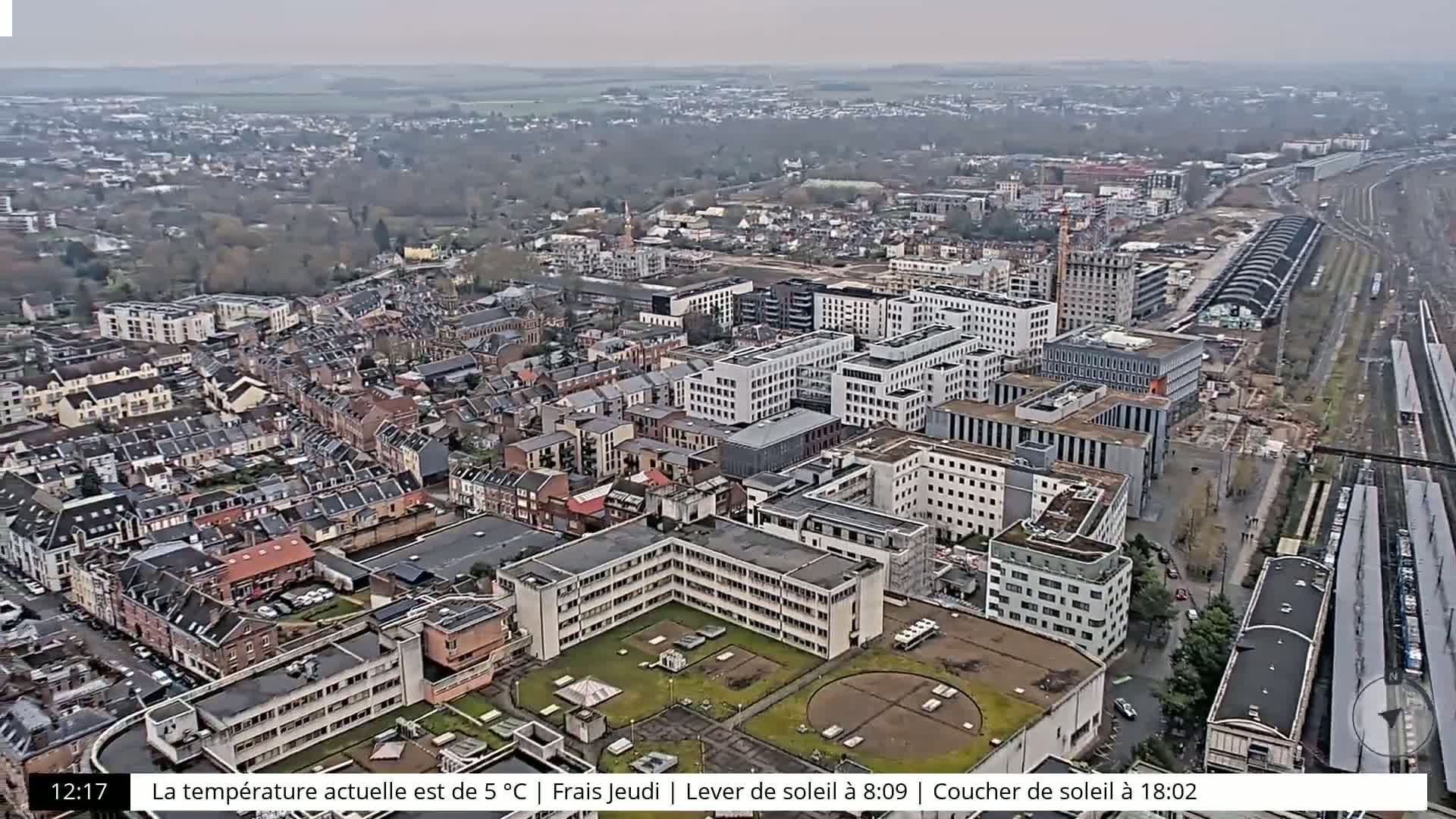 An aerial view shows a city with many buildings on a cloudy day.