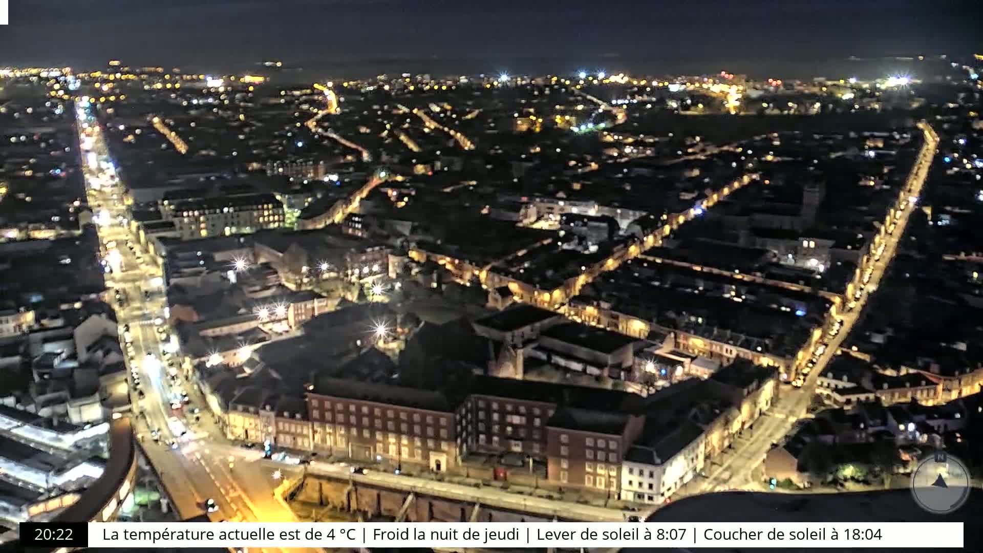 A nighttime aerial view of a city with illuminated streets and buildings under a clear sky.