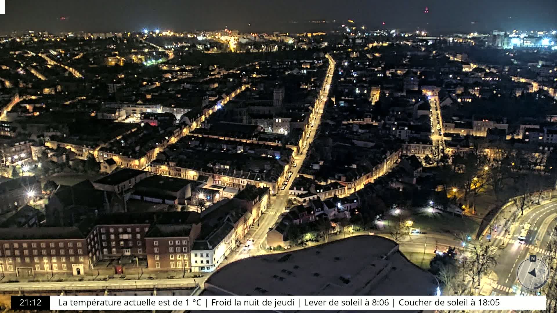 A nighttime aerial view of a city with illuminated streets and buildings.
