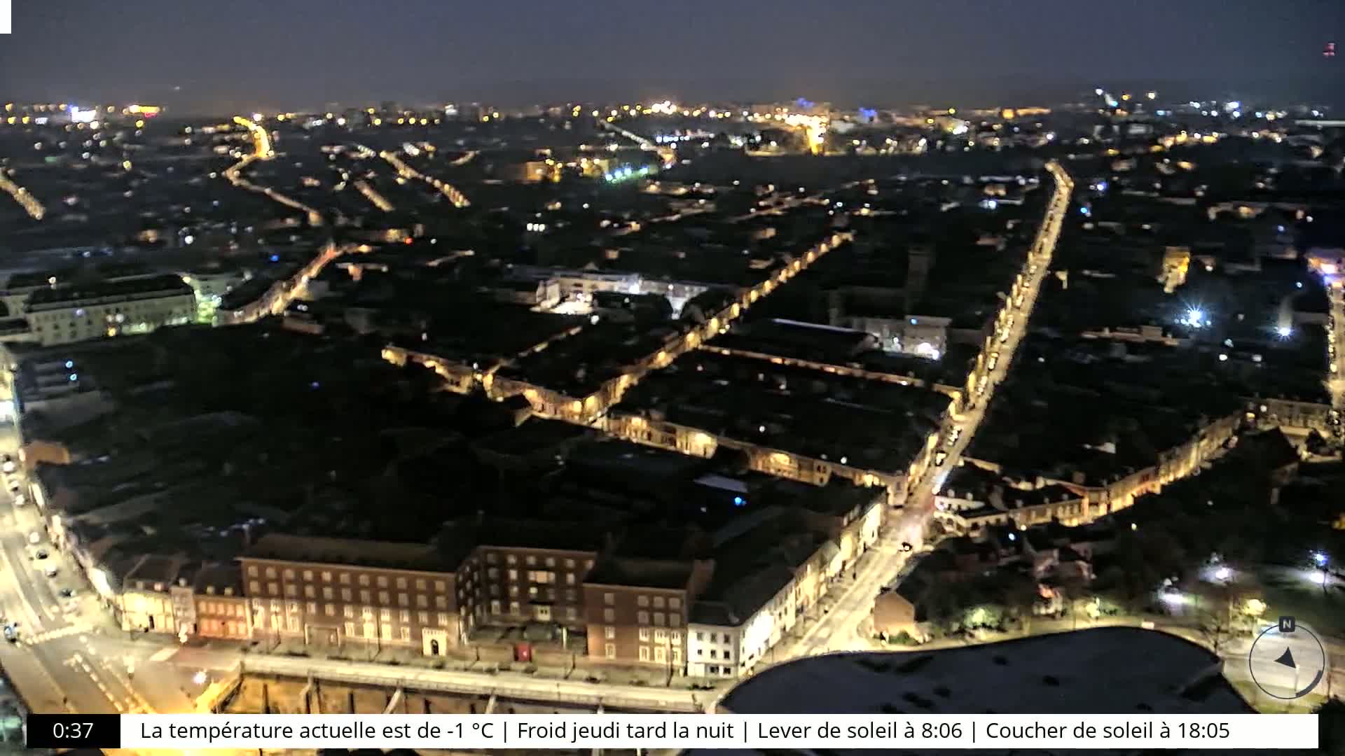A nighttime aerial view of a city with illuminated streets and buildings under a clear sky.