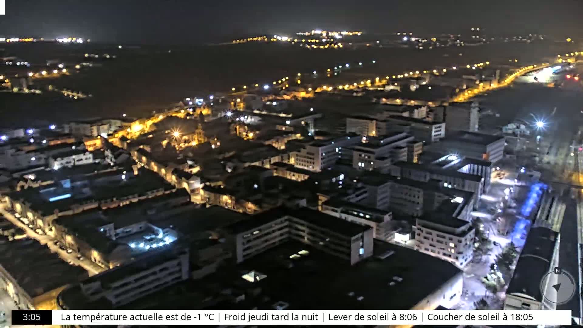 A nighttime aerial view of a city with its lights illuminated, under a clear, cold sky.