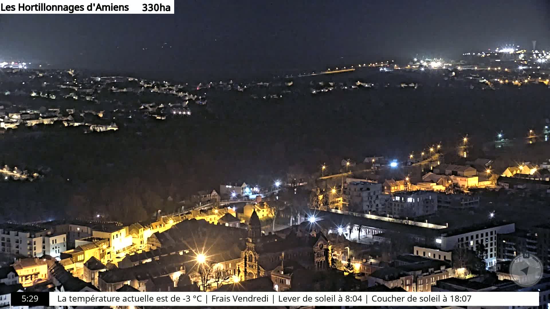 A nighttime aerial view of a city with numerous illuminated buildings and streets.