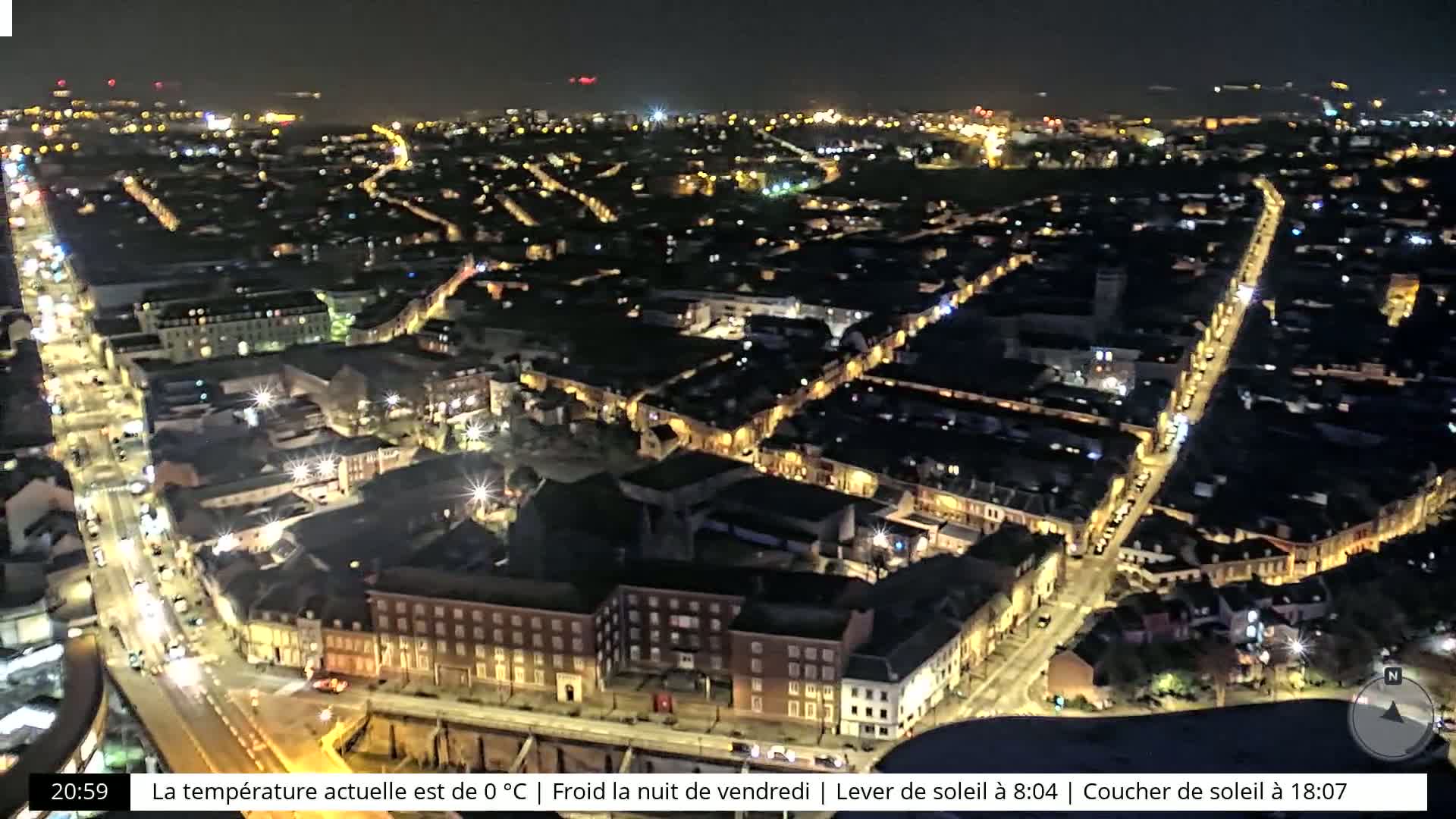 A nighttime aerial view of a city with brightly lit streets and buildings, under a clear sky.
