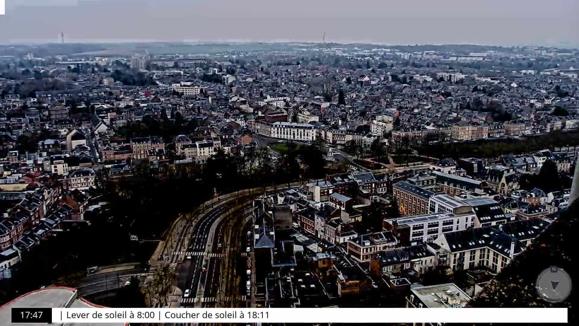 A high-angle, long shot of a city on an overcast day, showing a dense collection of buildings and roads.