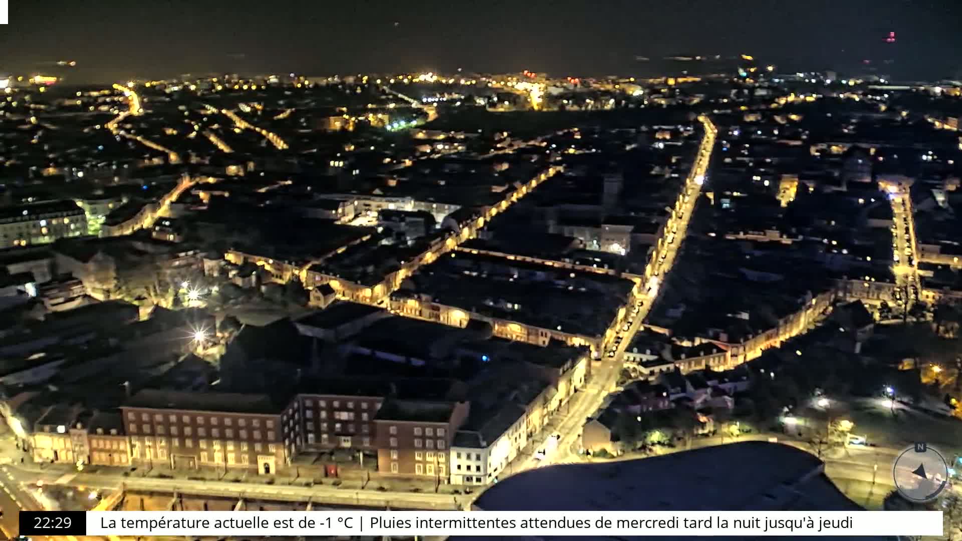 A nighttime aerial view of a city with illuminated streets and buildings.