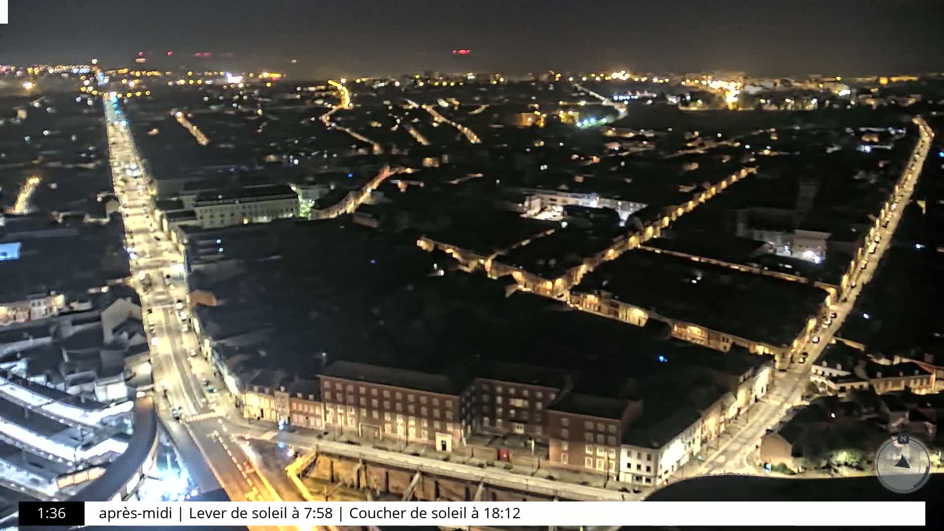 A nighttime aerial view shows a city with illuminated streets and buildings.