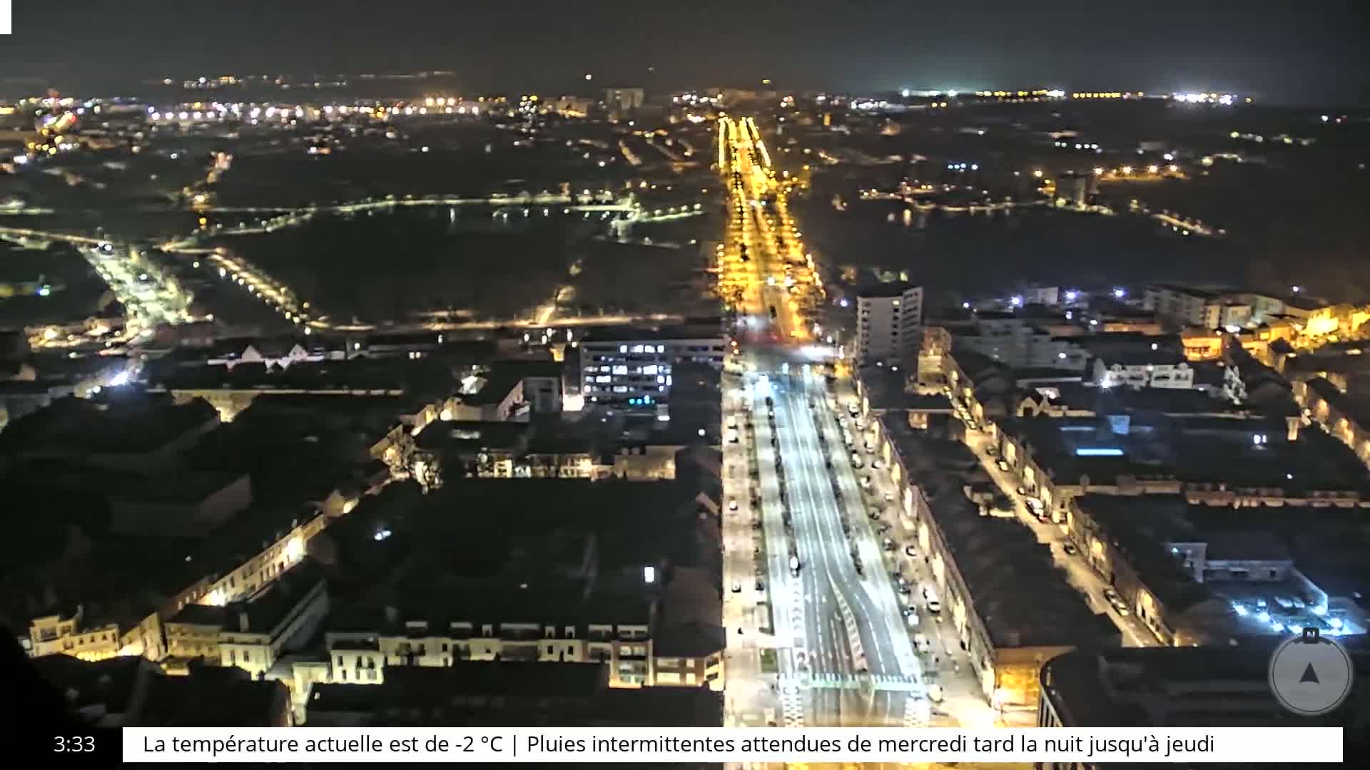A nighttime aerial view of a city with brightly lit streets and buildings under a clear, dark sky.