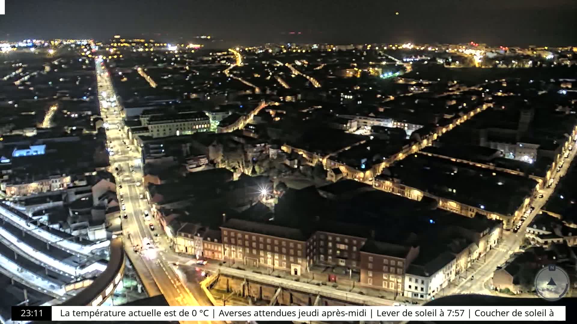 A nighttime aerial view of a city with illuminated streets and buildings under a clear sky.