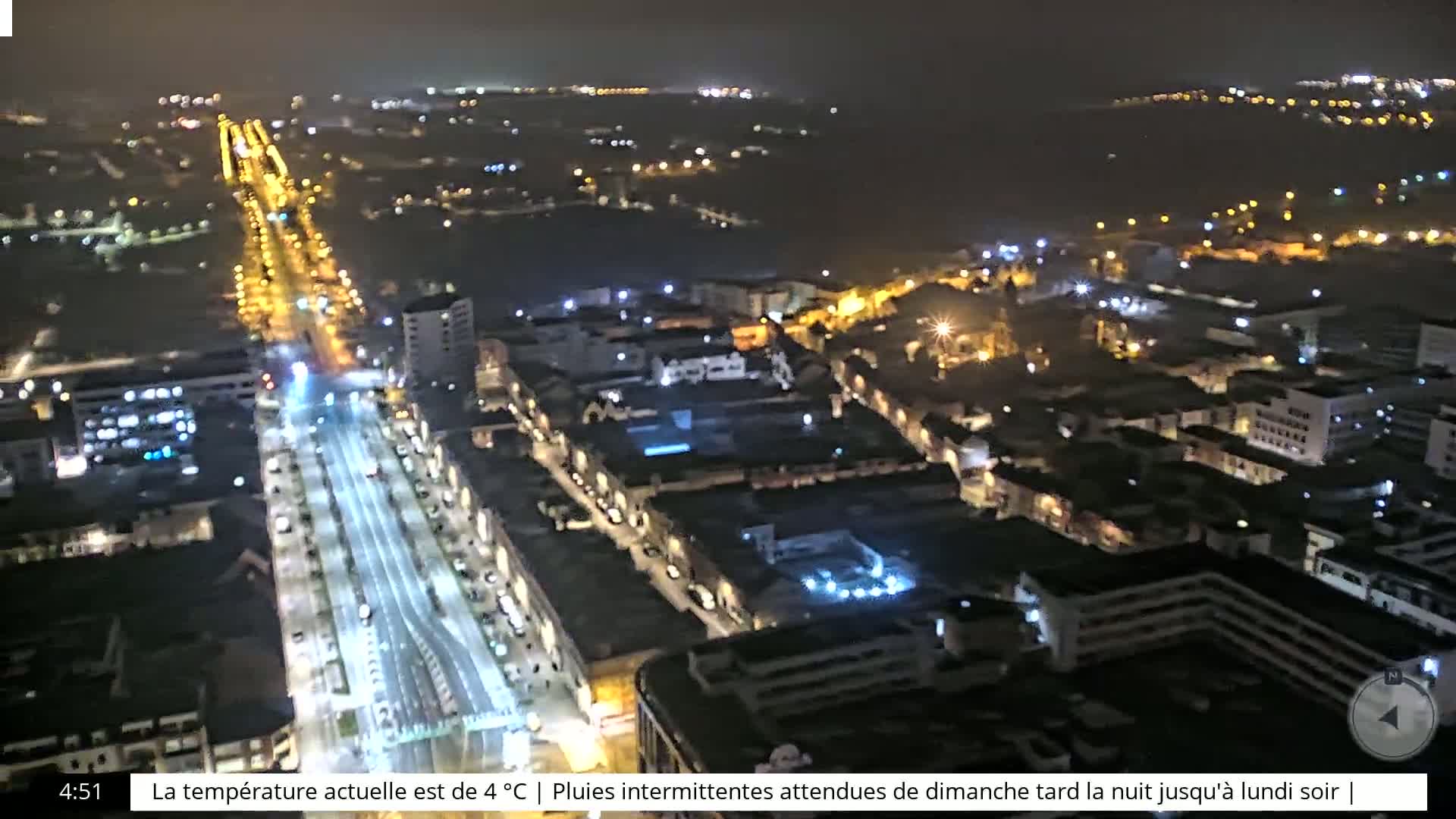 A nighttime aerial view of a city with brightly lit streets and buildings.