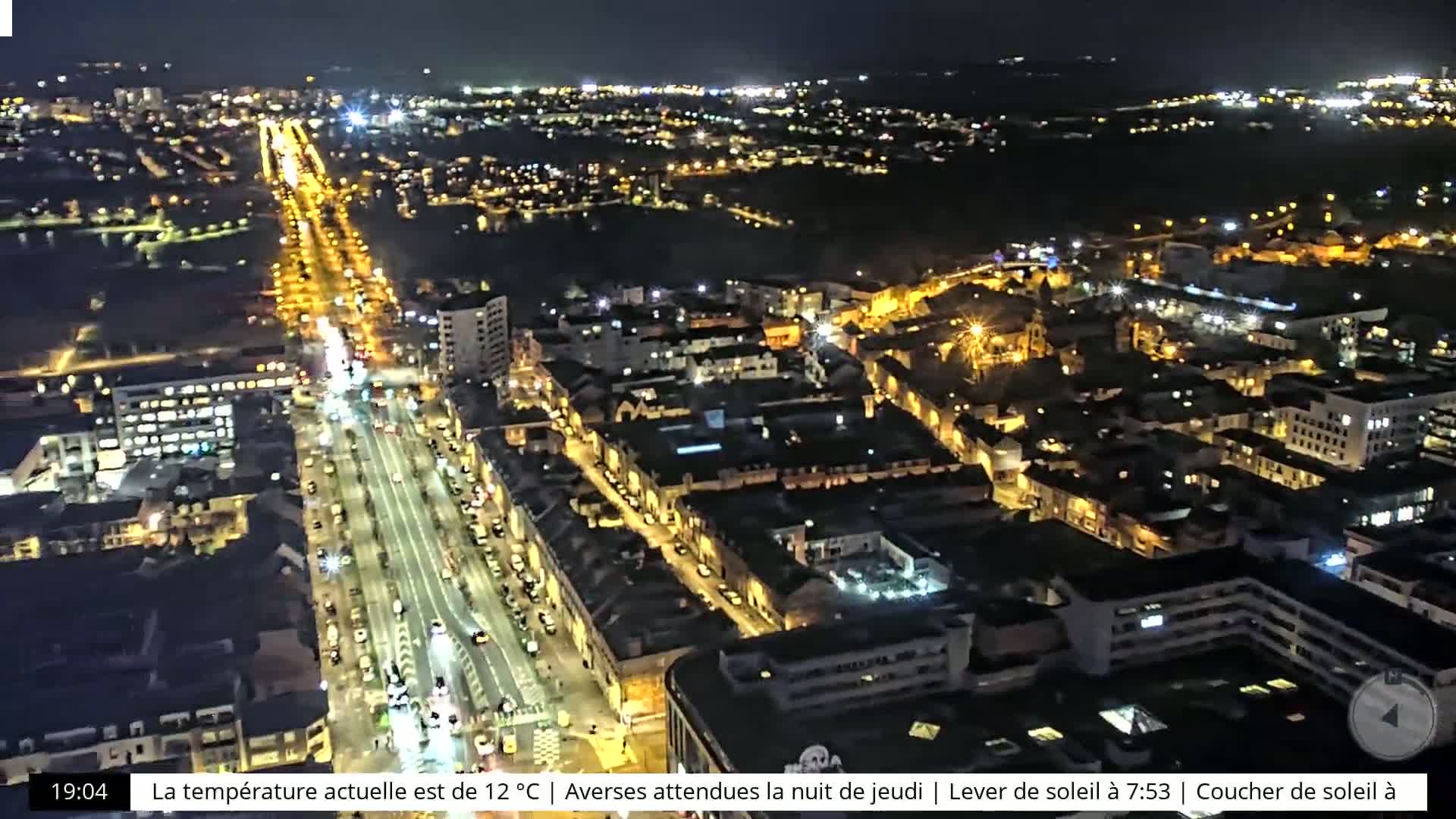 A nighttime aerial view of a city with illuminated streets and buildings under a clear sky.