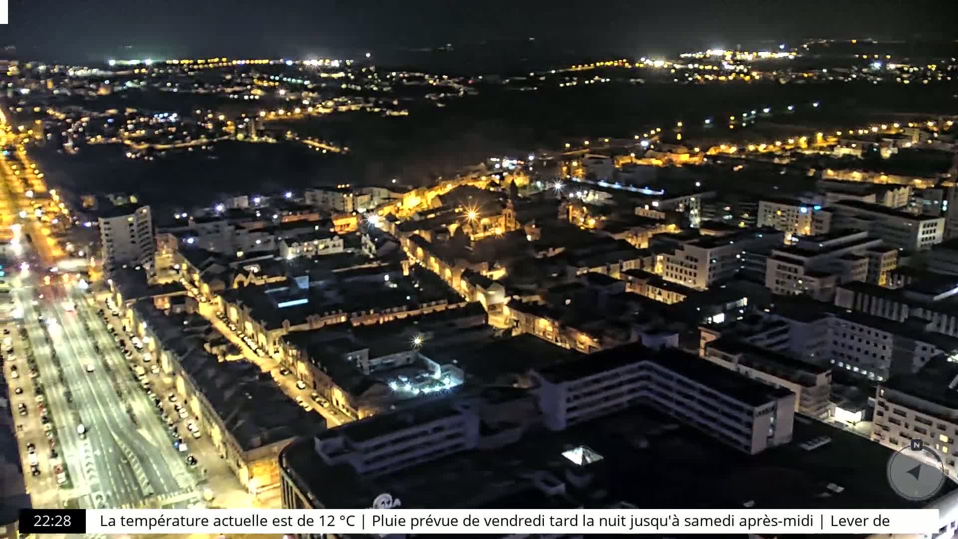 A nighttime aerial view of a city illuminated by streetlights, with a clear sky.
