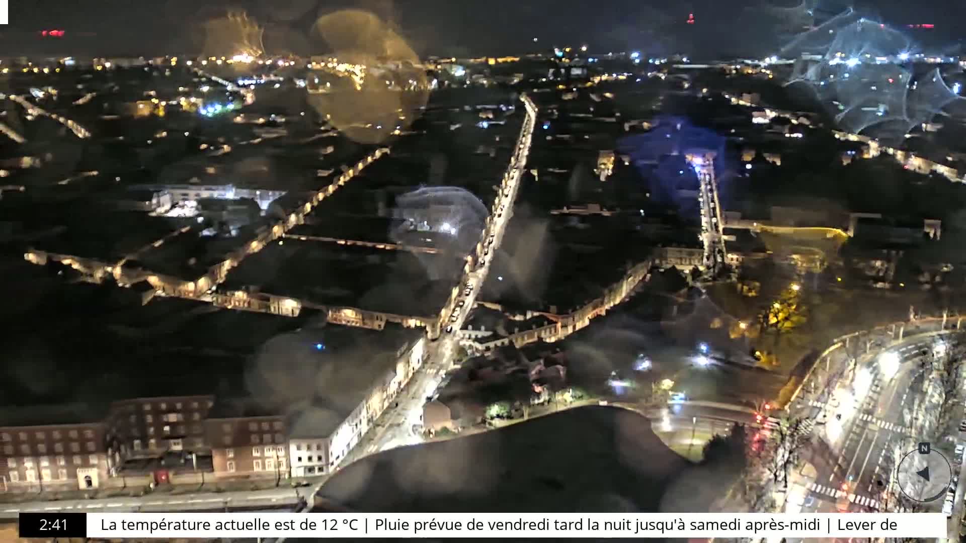 A nighttime aerial view of a city with illuminated streets and buildings.