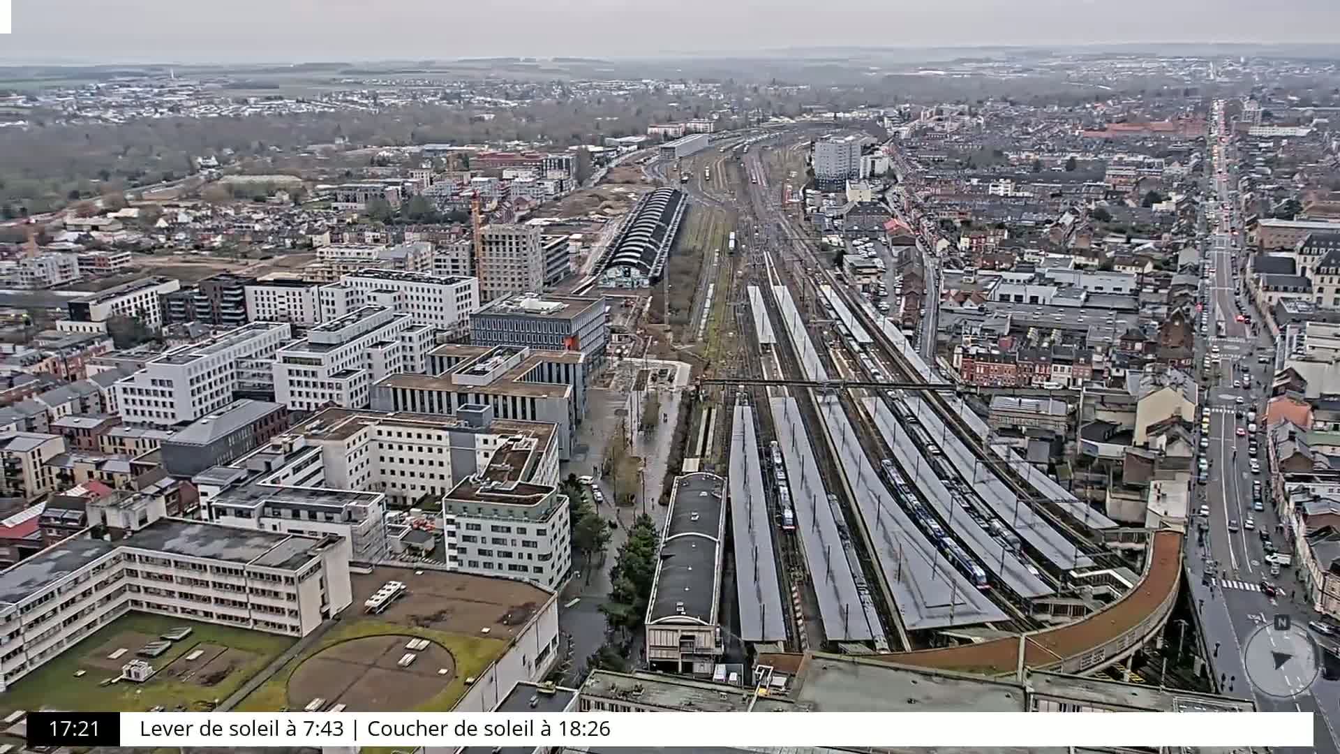 A high-angle, long shot of a city with a large train station on an overcast day.
