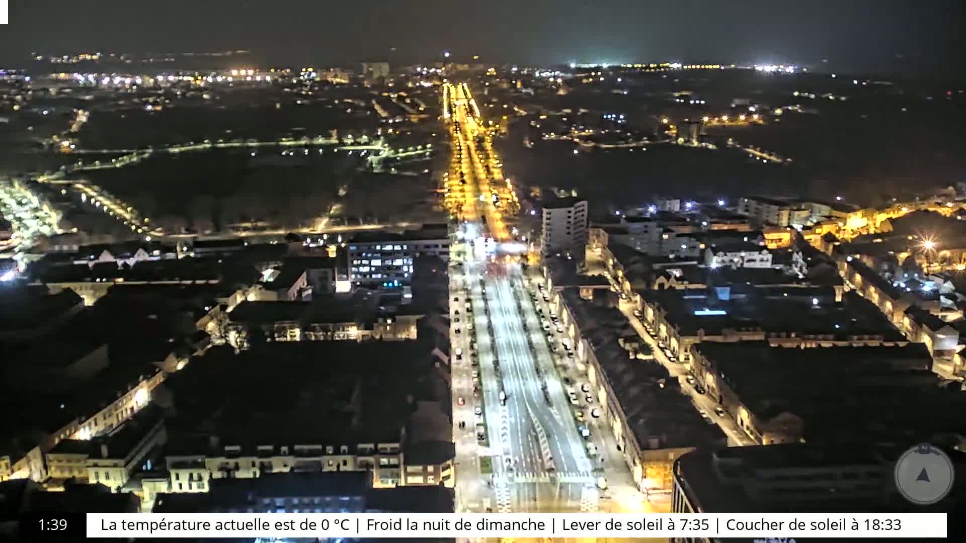 A nighttime aerial view of a city with brightly lit streets and buildings, under a clear sky.