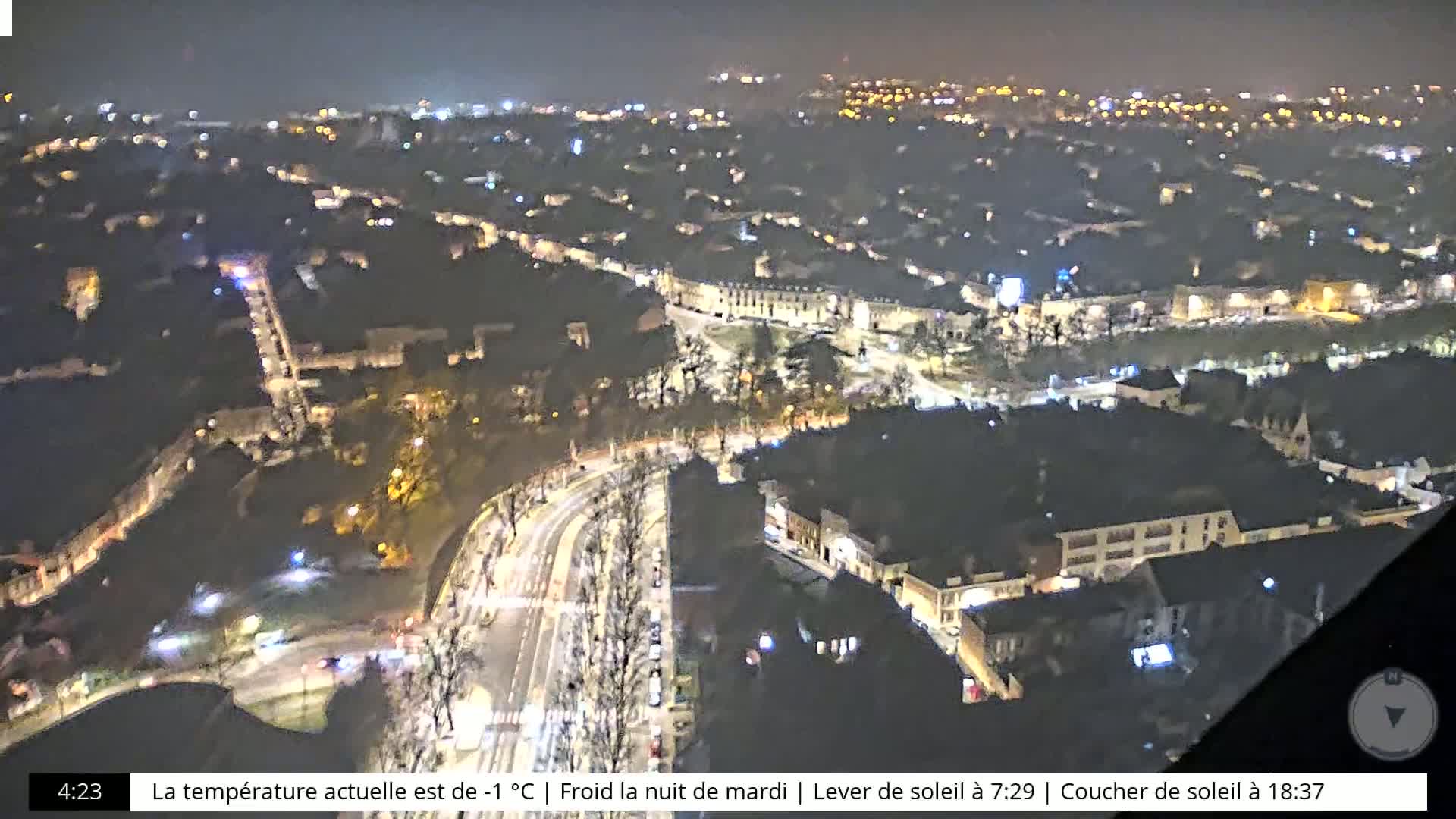 A nighttime, aerial view of a city with dimly lit streets and buildings under a clear, cold sky.
